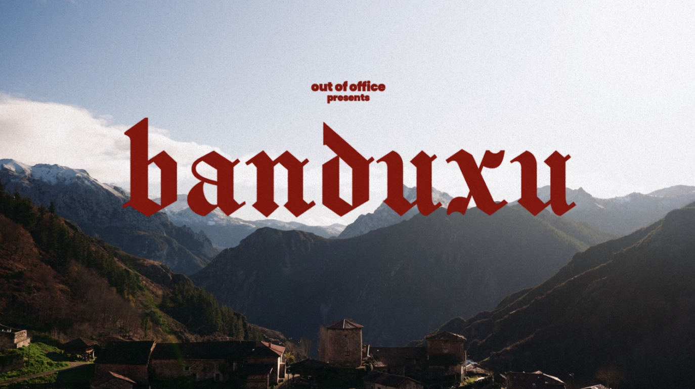 Mountain landscape with a small village, and text overlay that says 'out of office presents handux' in red lettering.