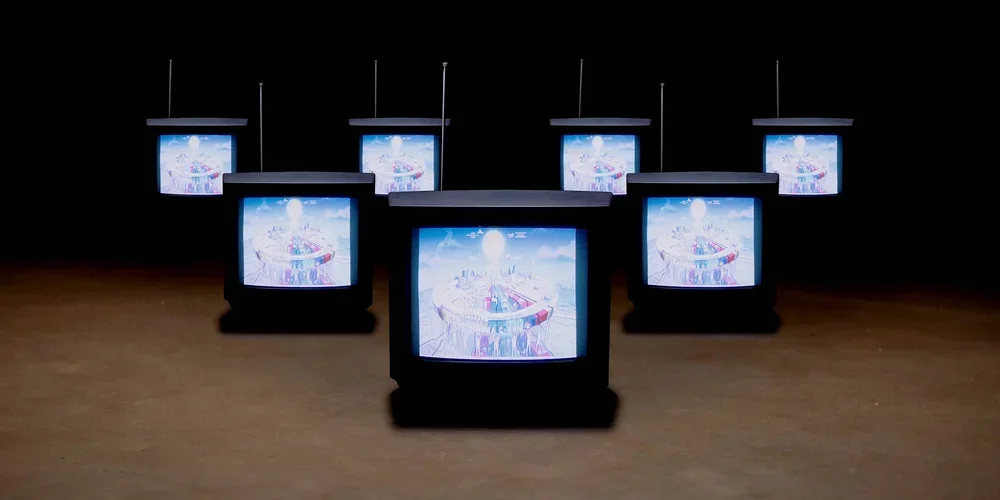 Multiple old television sets displaying animated scenes, arranged on a wooden floor in a dark room.