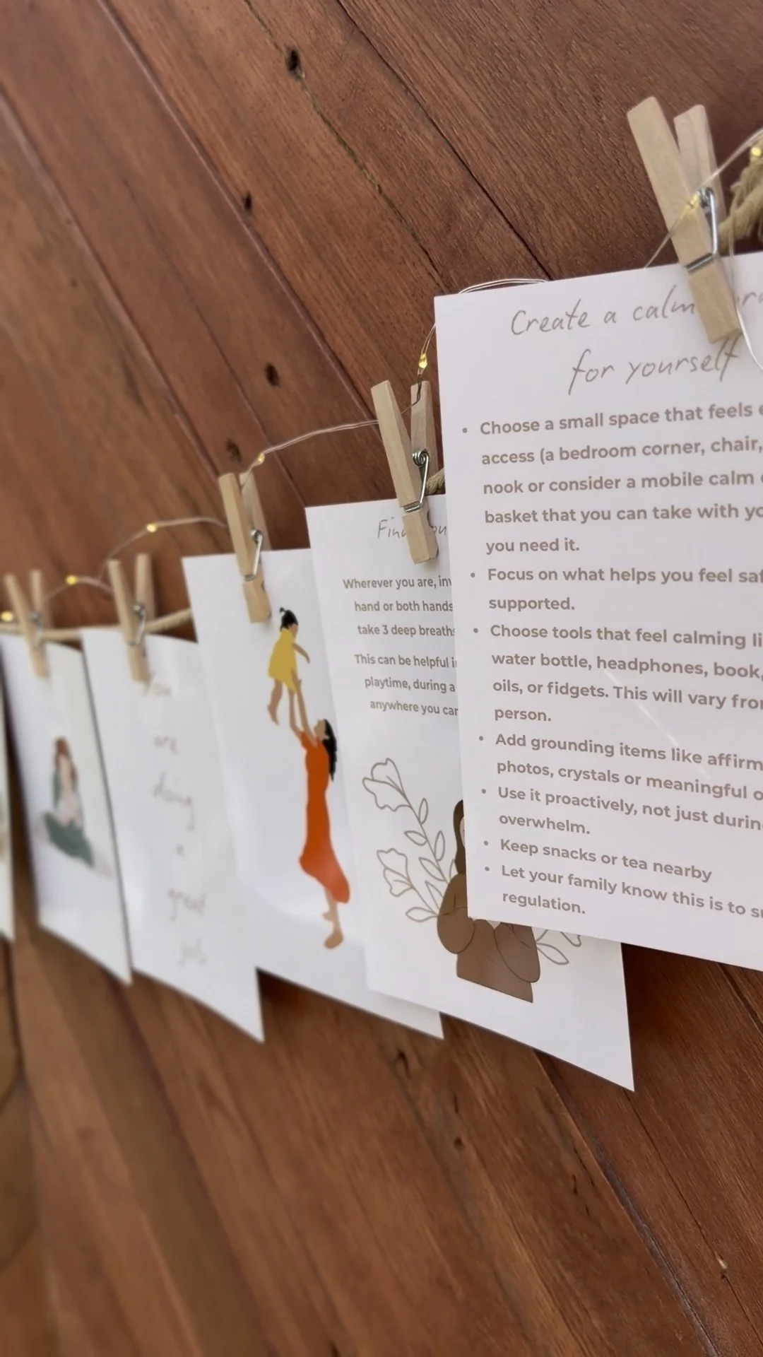 A display of printed papers hanging on a string with small clothespins attached to a wooden wall, each with different illustrations and text.