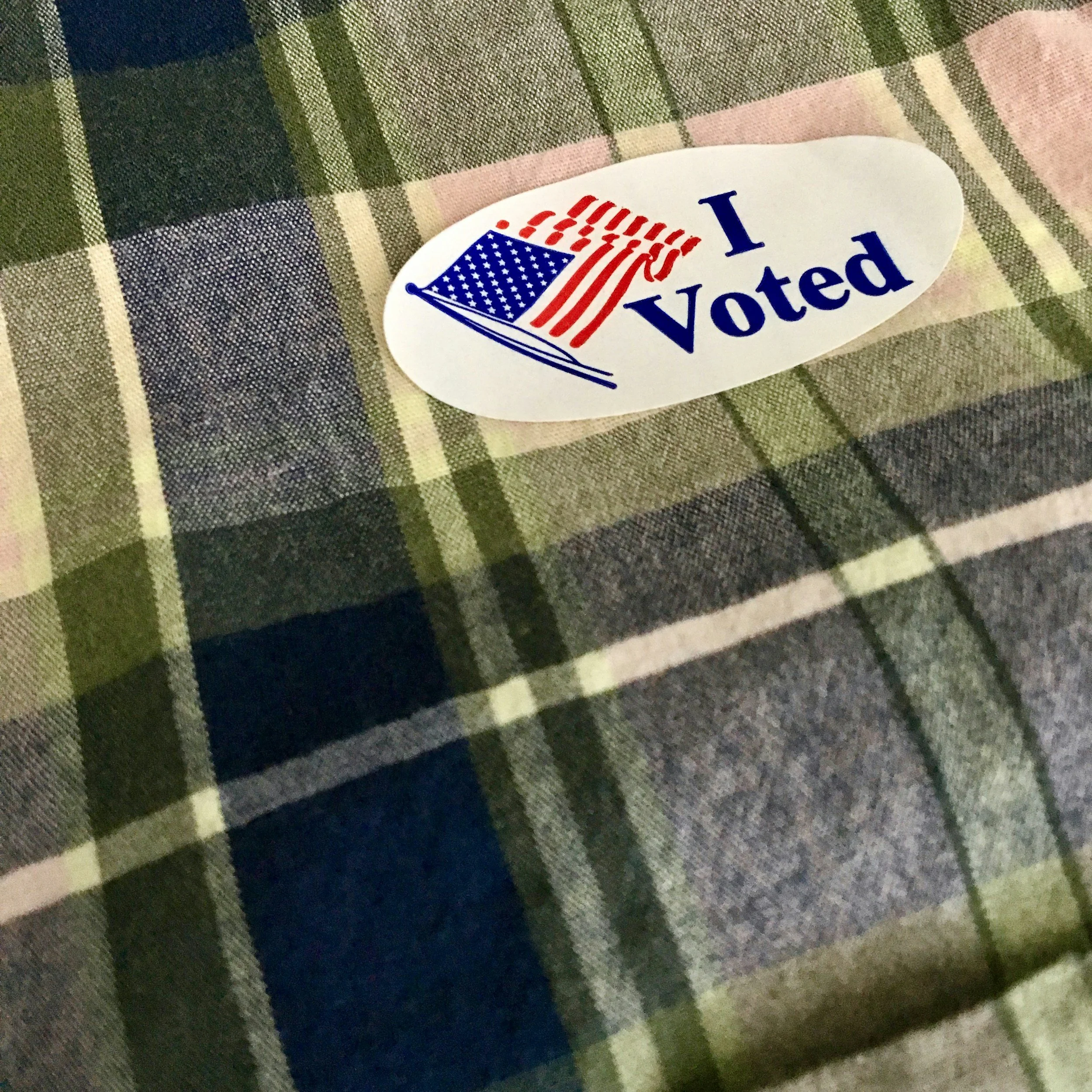 I voted sticker on a flannel shirt