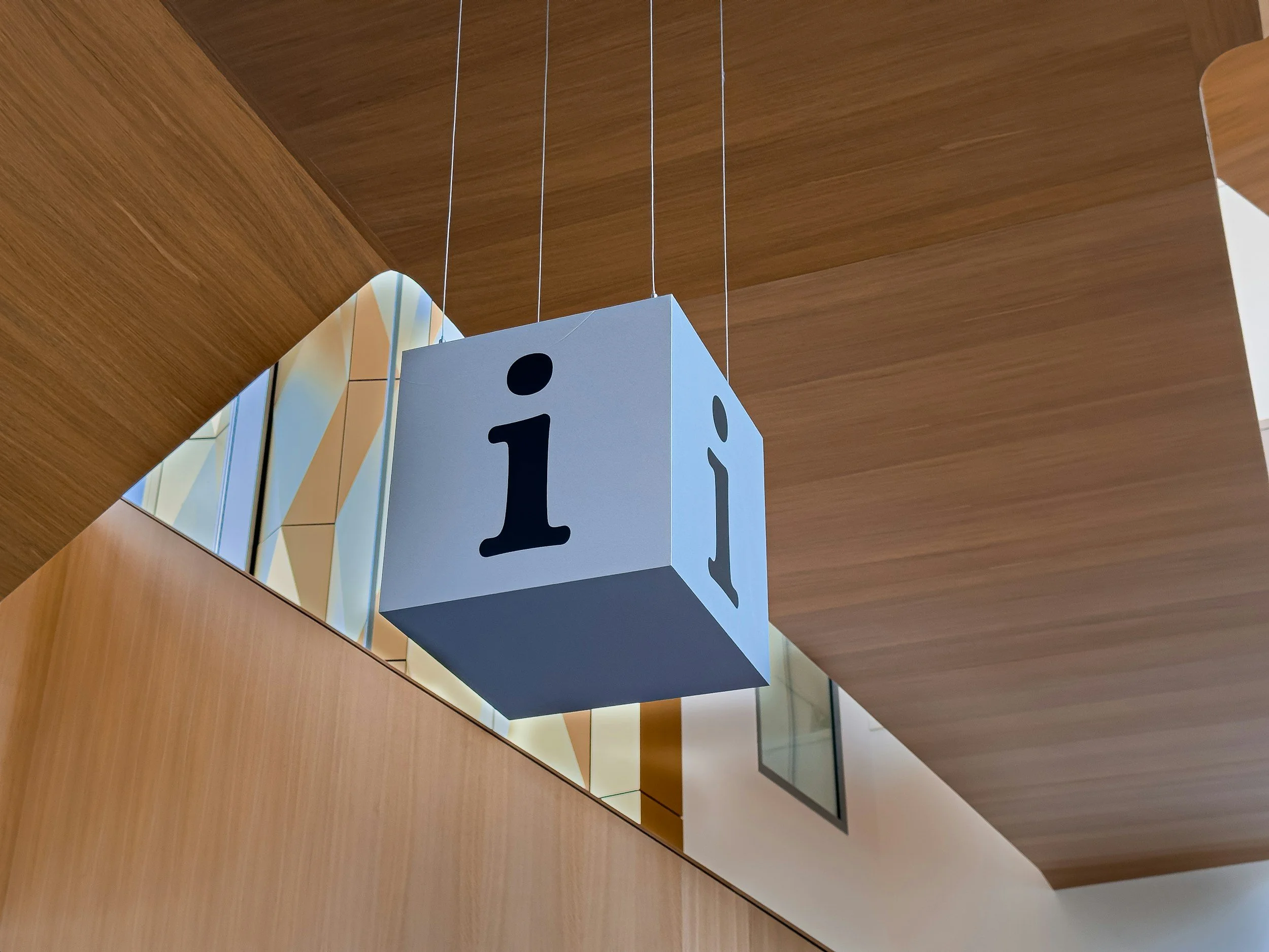 Blue cube hanging from the ceiling with a lower case "i"