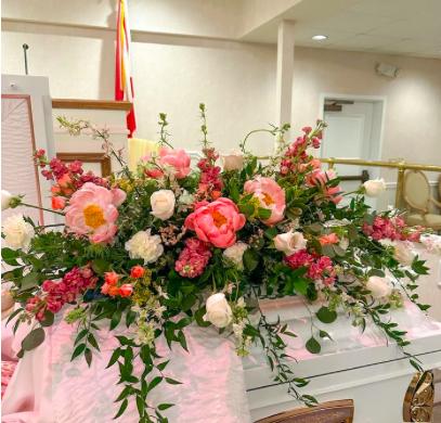 Large floral arrangement with pink and white flowers on a white piano.