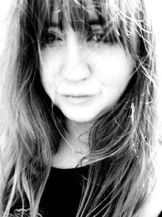 Black and white close-up photo of a woman with long, wind-blown hair partially covering her face.
