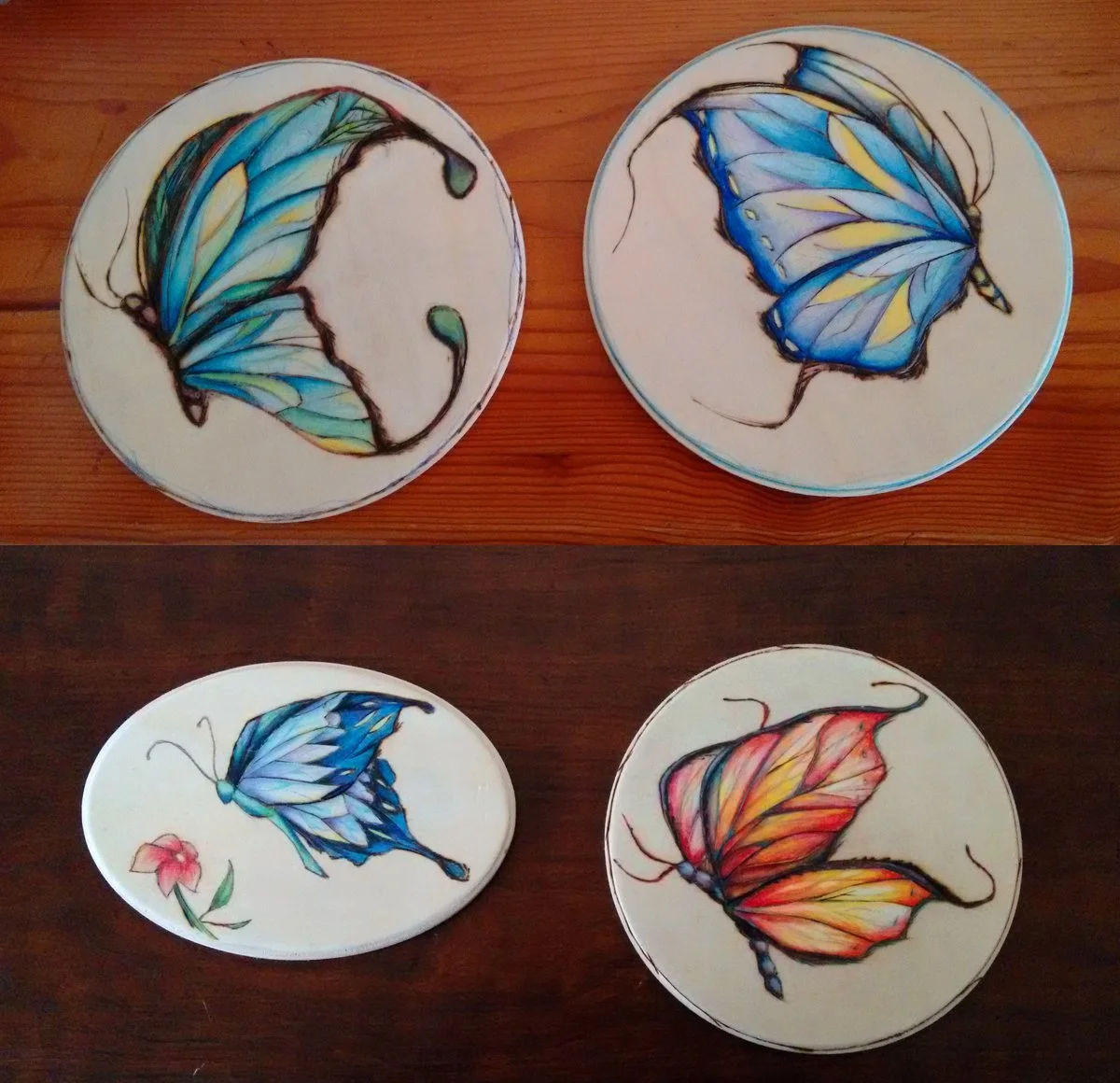 Set of four colorful butterfly designs burned into hardwood panels using pyrography, two with blue butterflies and two with red and orange butterflies