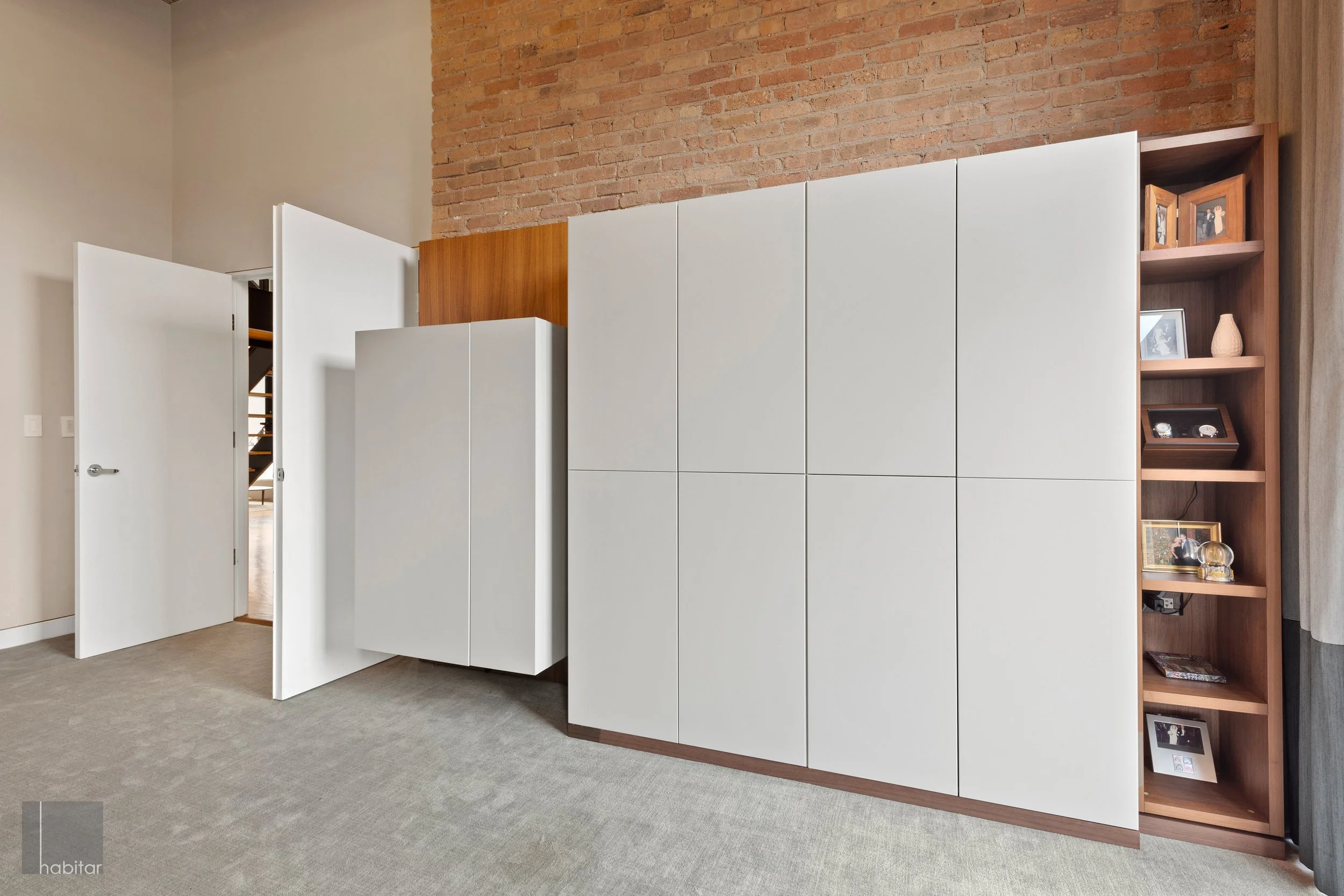 Modern interior with white cabinets, wooden shelves, and exposed brick wall in background.