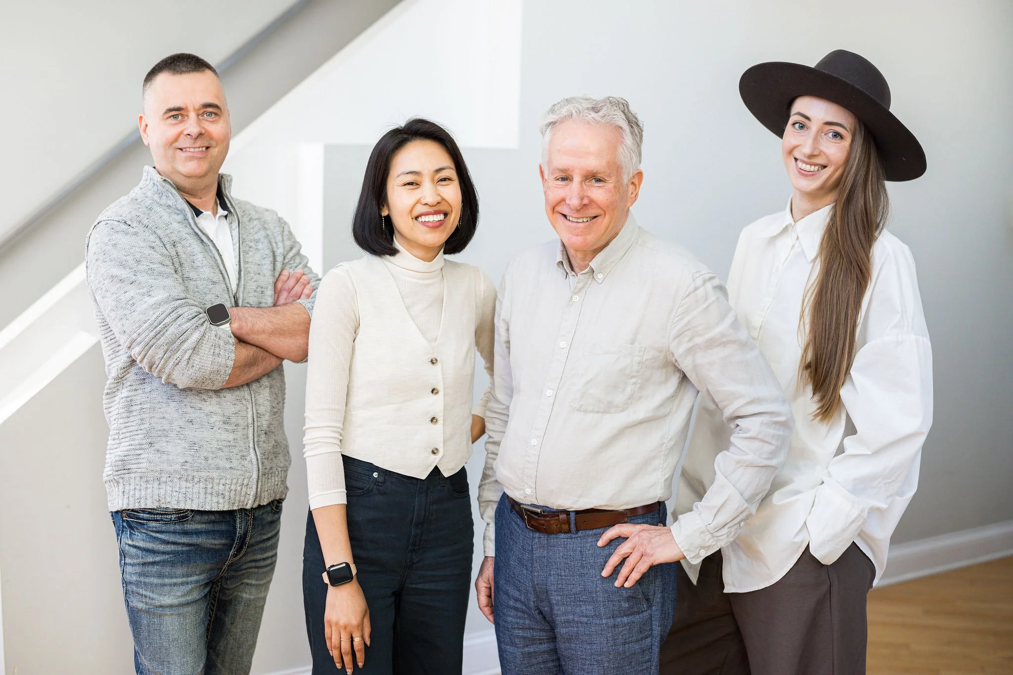 Group of five diverse adults standing indoors, smiling for the camera.