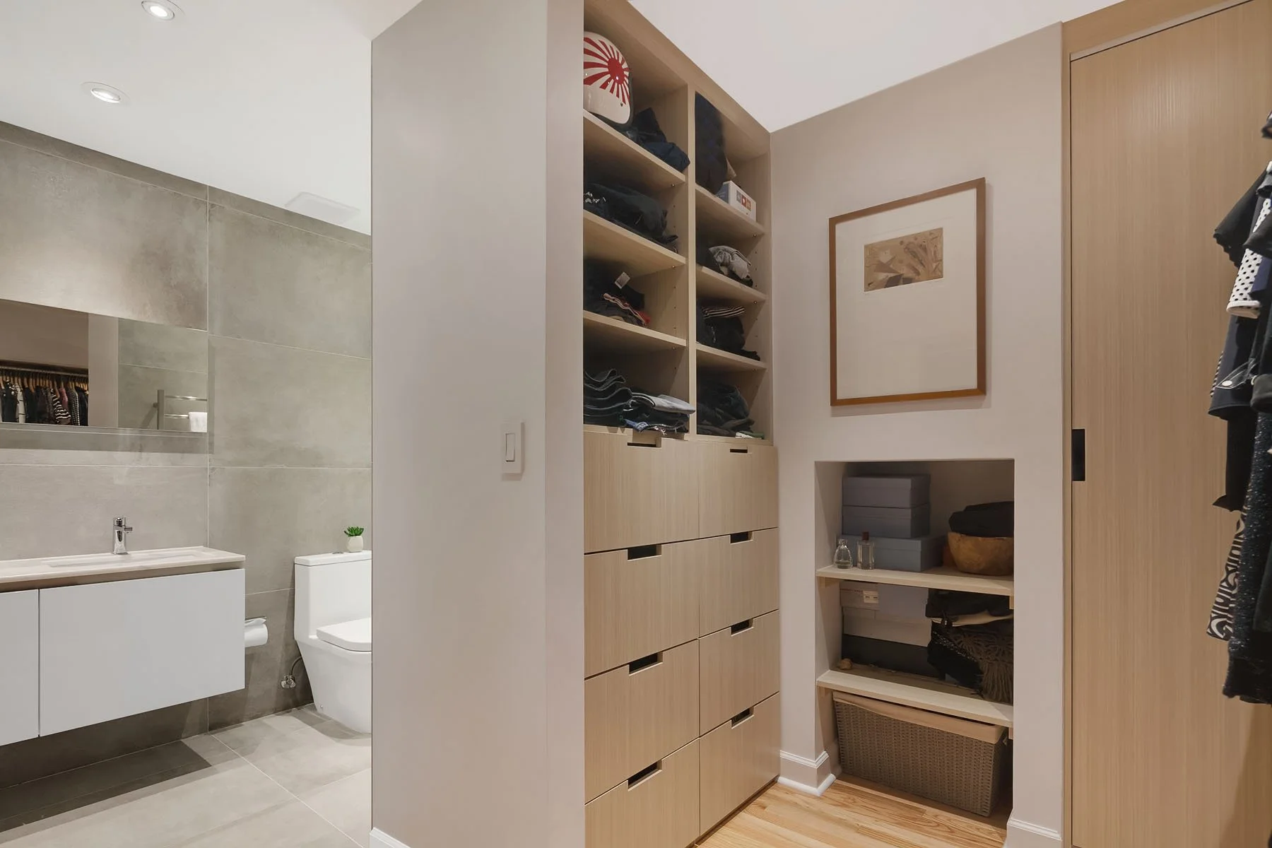 Walk-in closet with shelves and drawers, and a bathroom with a sink and toilet visible in the background.