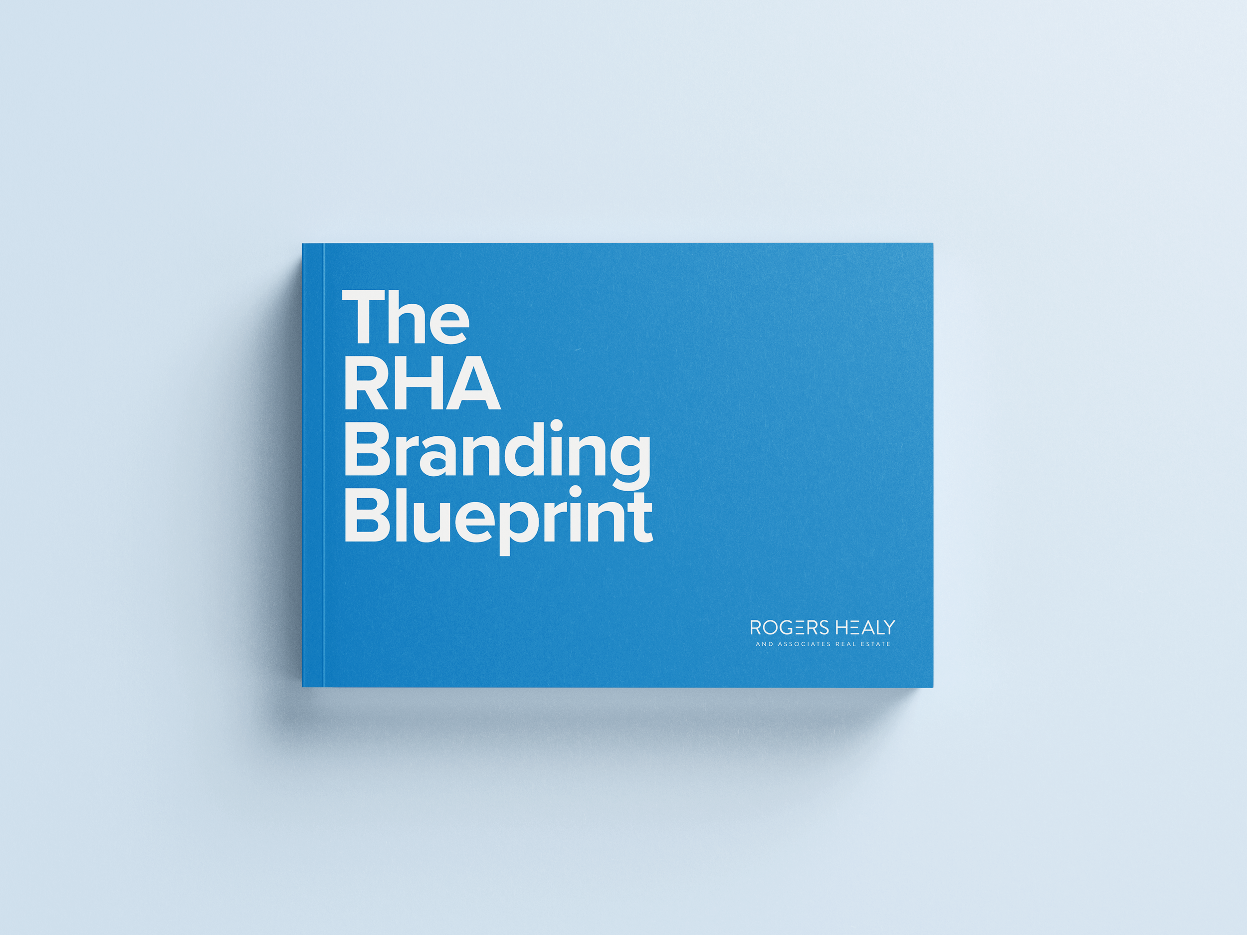 A blue hardcover book titled "The RHA Branding Blueprint" by Rogers Healy, placed on a light blue background.