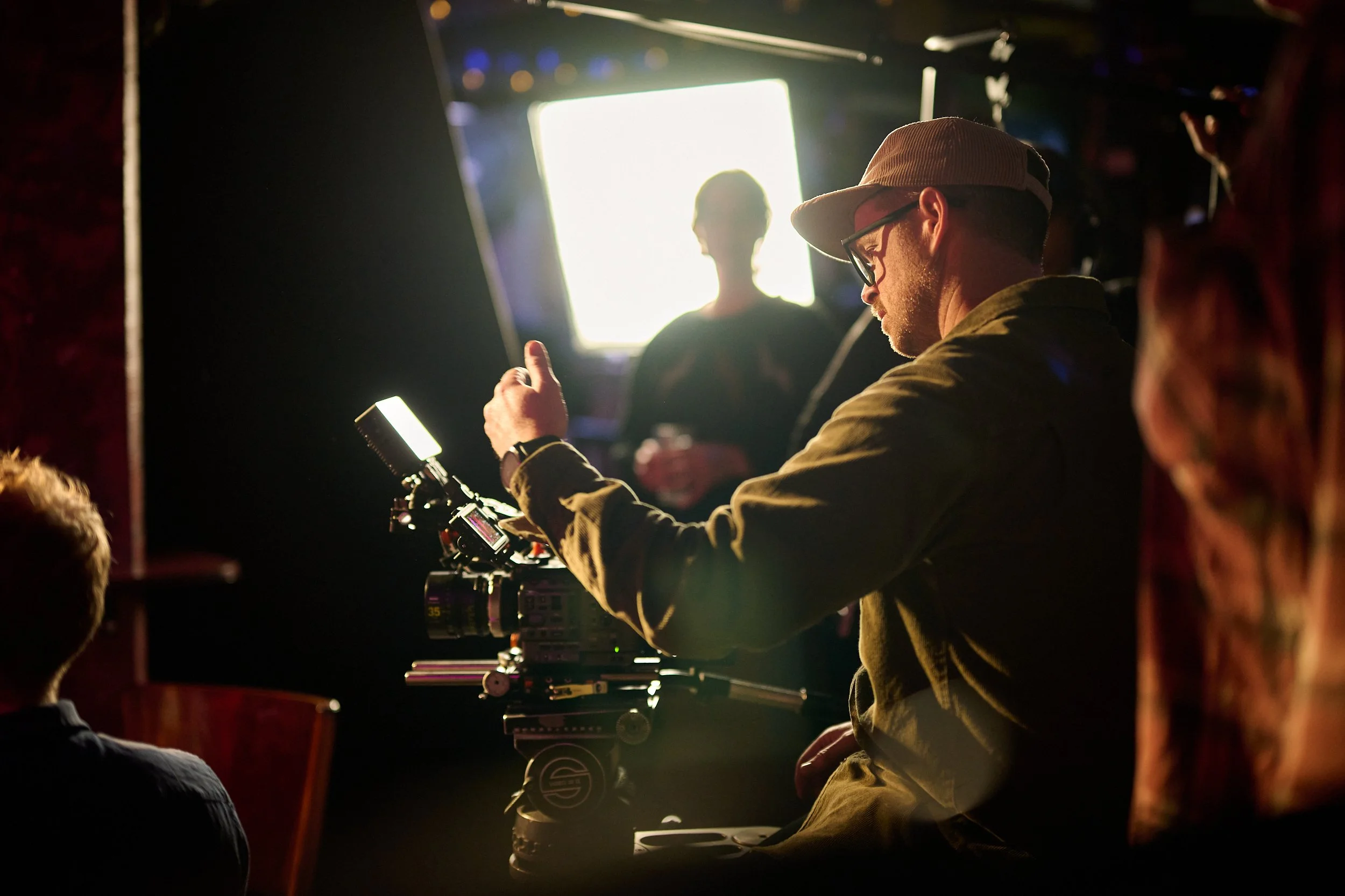 Camera operator Hamish McCormick reviewing camera footage while filming the Statistics New Zealand commercial 'Data Helps Us Do in a dimly lit bar
