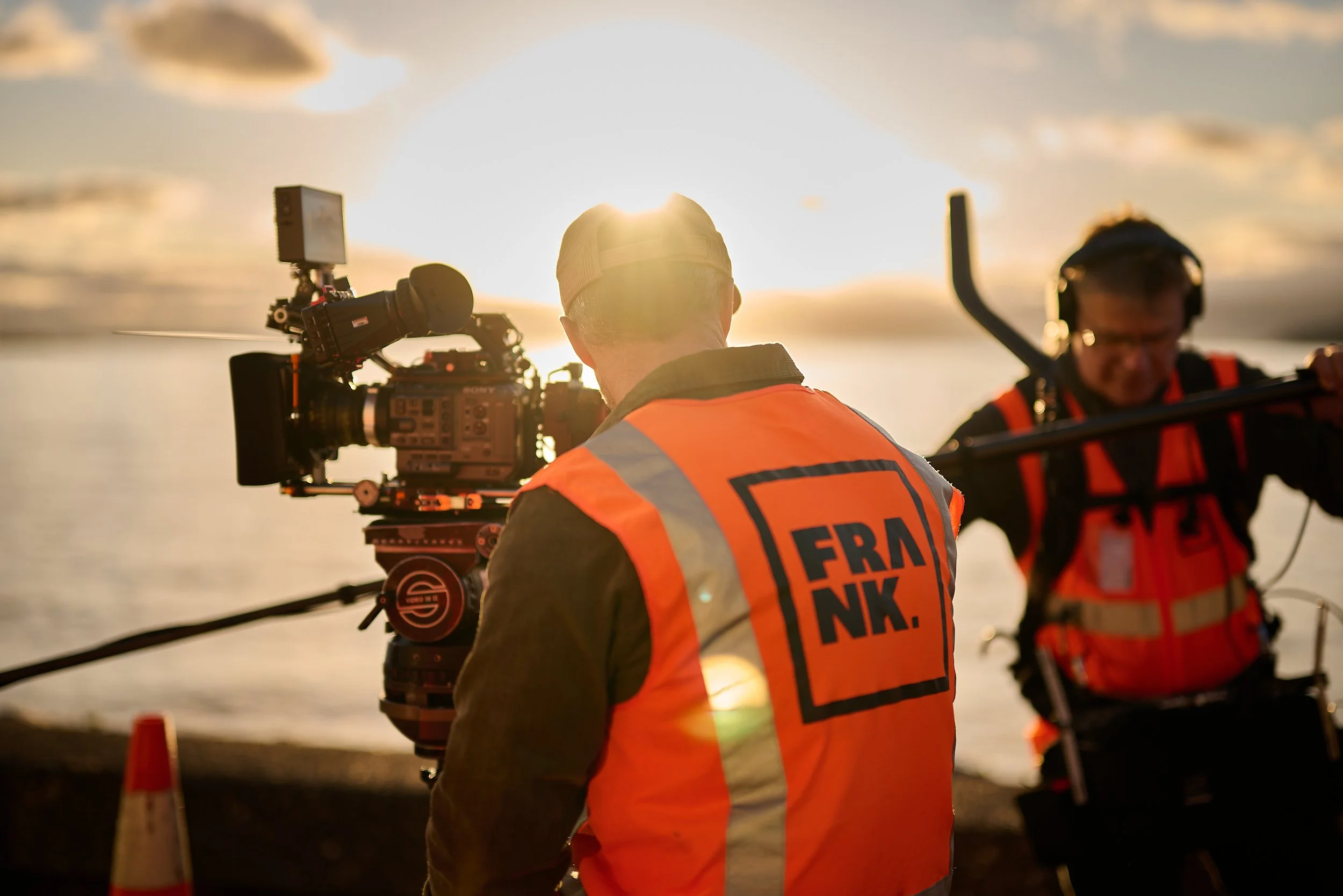 Hamish McCormick Camera operator with a Frank logo high vis and light flare