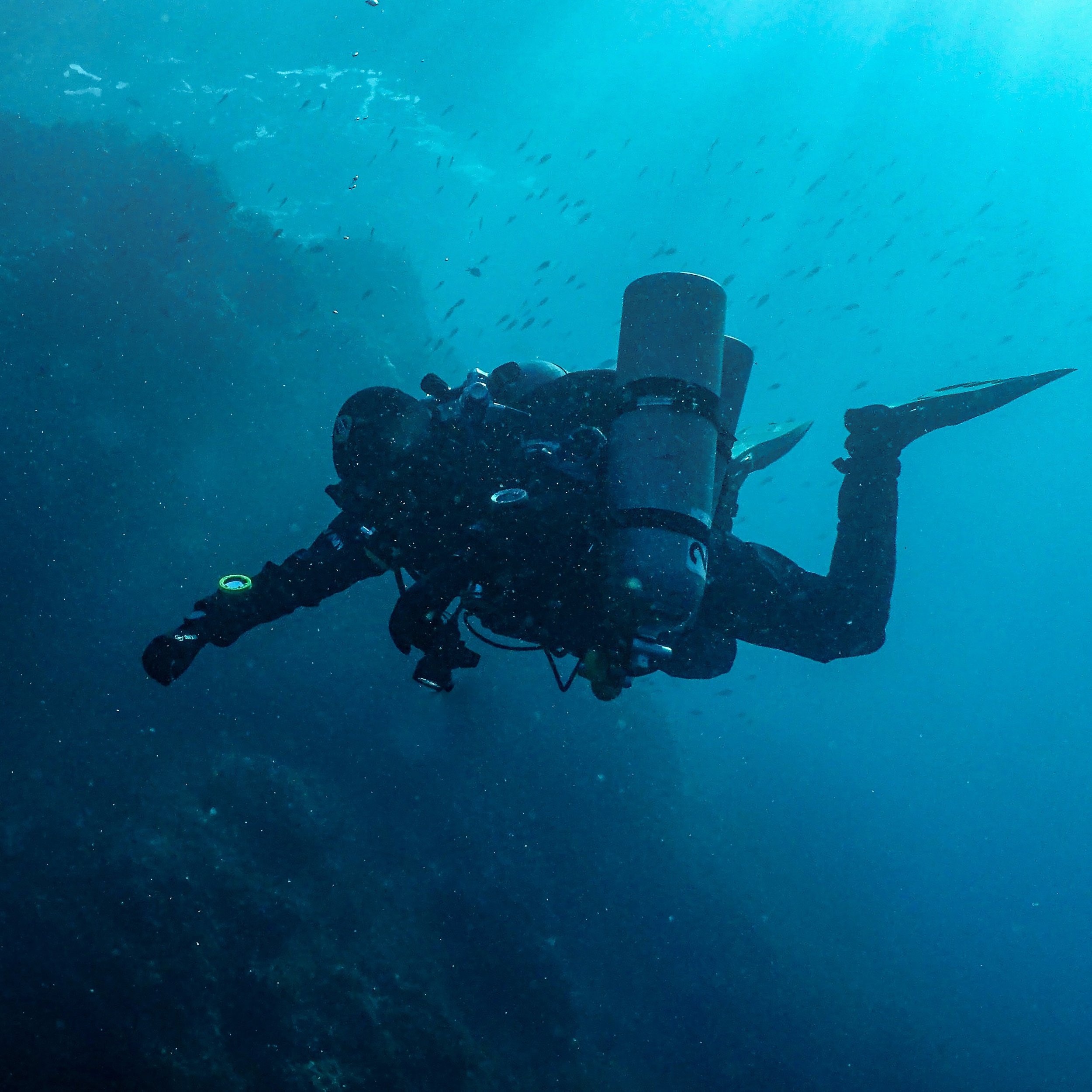 Sottomarino immerso in acque profonde con molti pesci che nuotano intorno.