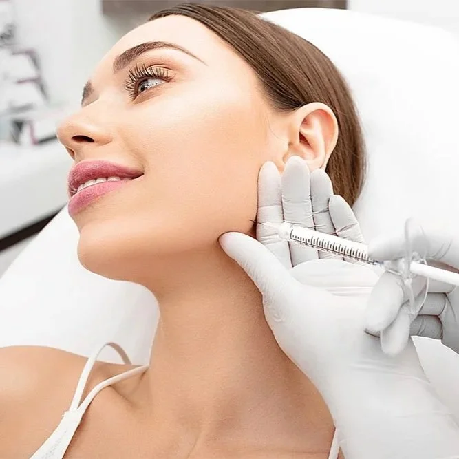 A woman receiving a cosmetic injection in her jawline from a medical professional wearing gloves.