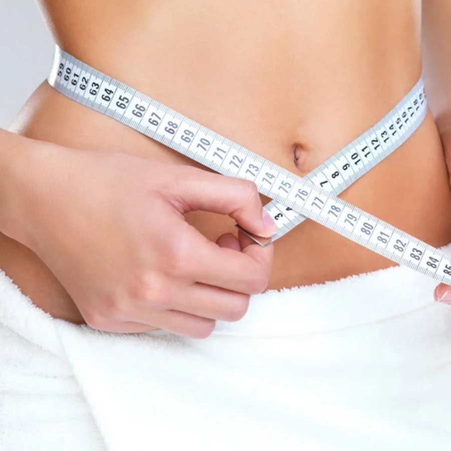 Person measuring their waist with a tape measure.