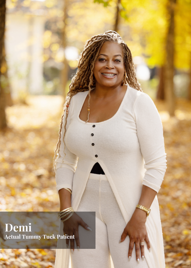 A smiling woman with long, blonde dreadlocks standing outdoors in a park with fallen leaves and trees in autumn. She is wearing a cream-colored cardigan and matching pants, with jewelry and braces on her teeth.