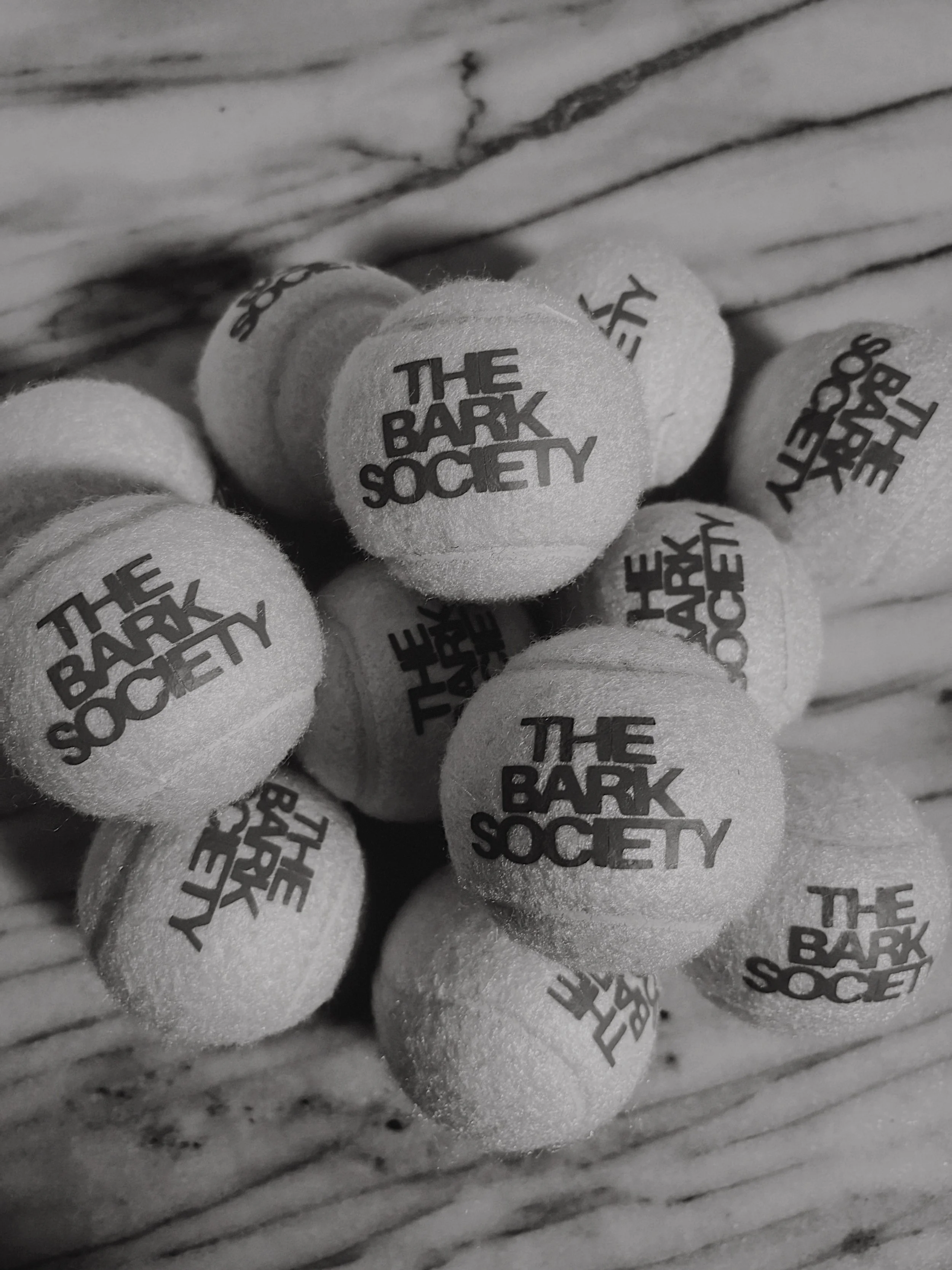 Close-up of foam tennis balls with the logo 'The Park Society' printed on them, placed on a textured surface.