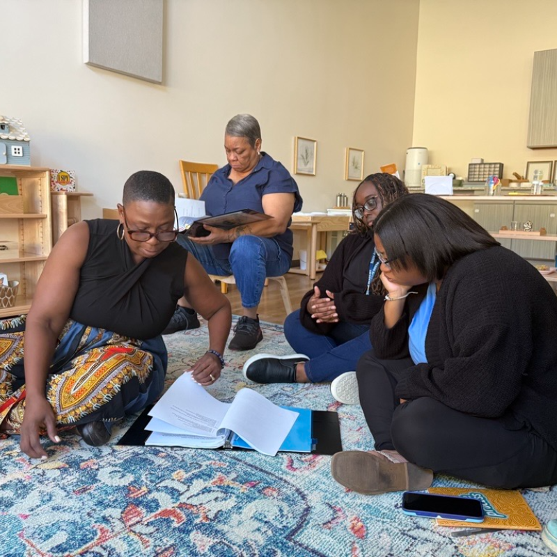 Four Montessori teachers reviewing their training manuals