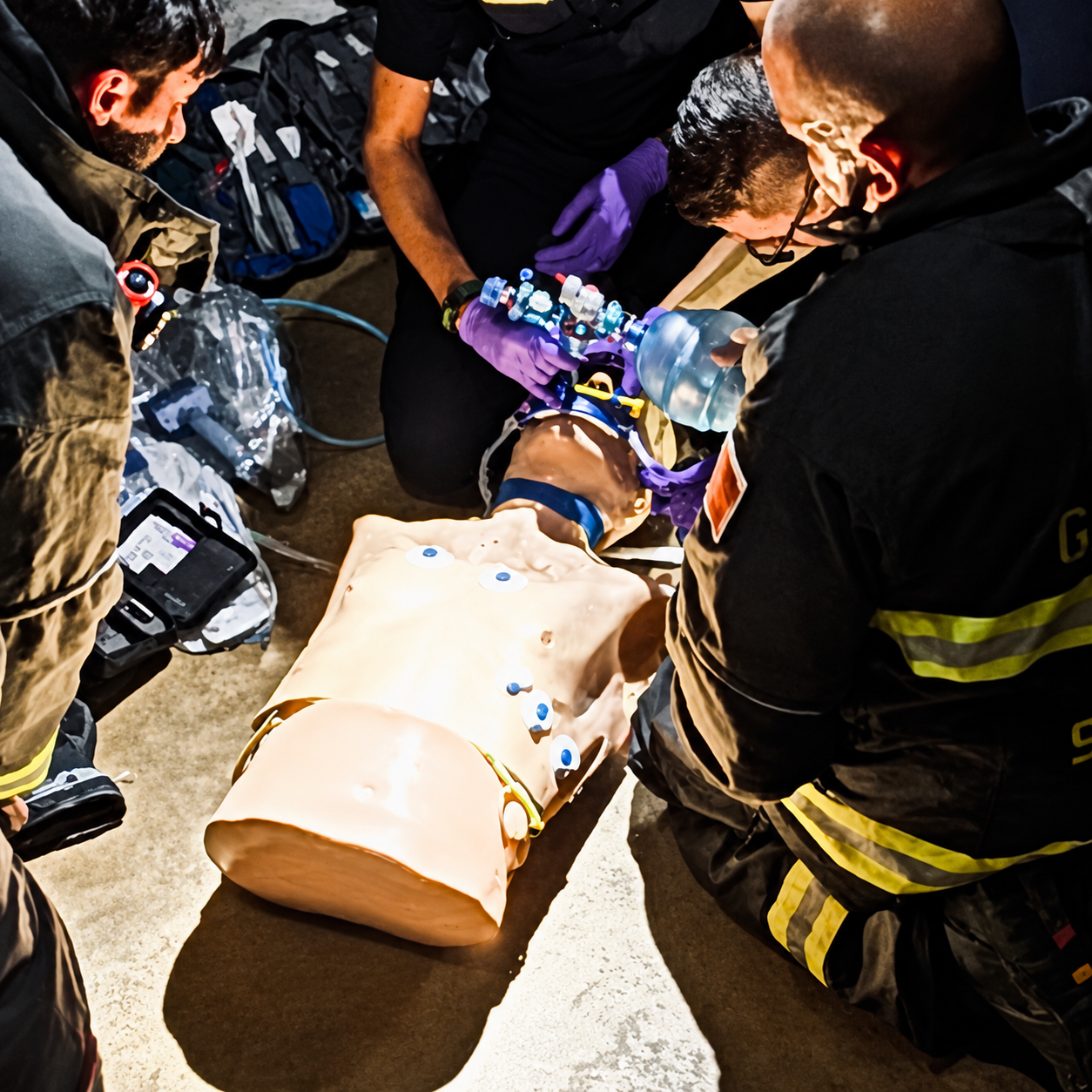 Emergency rescue team performing CPR training on a medical dummy with multiple sensors and a ventilation mask.