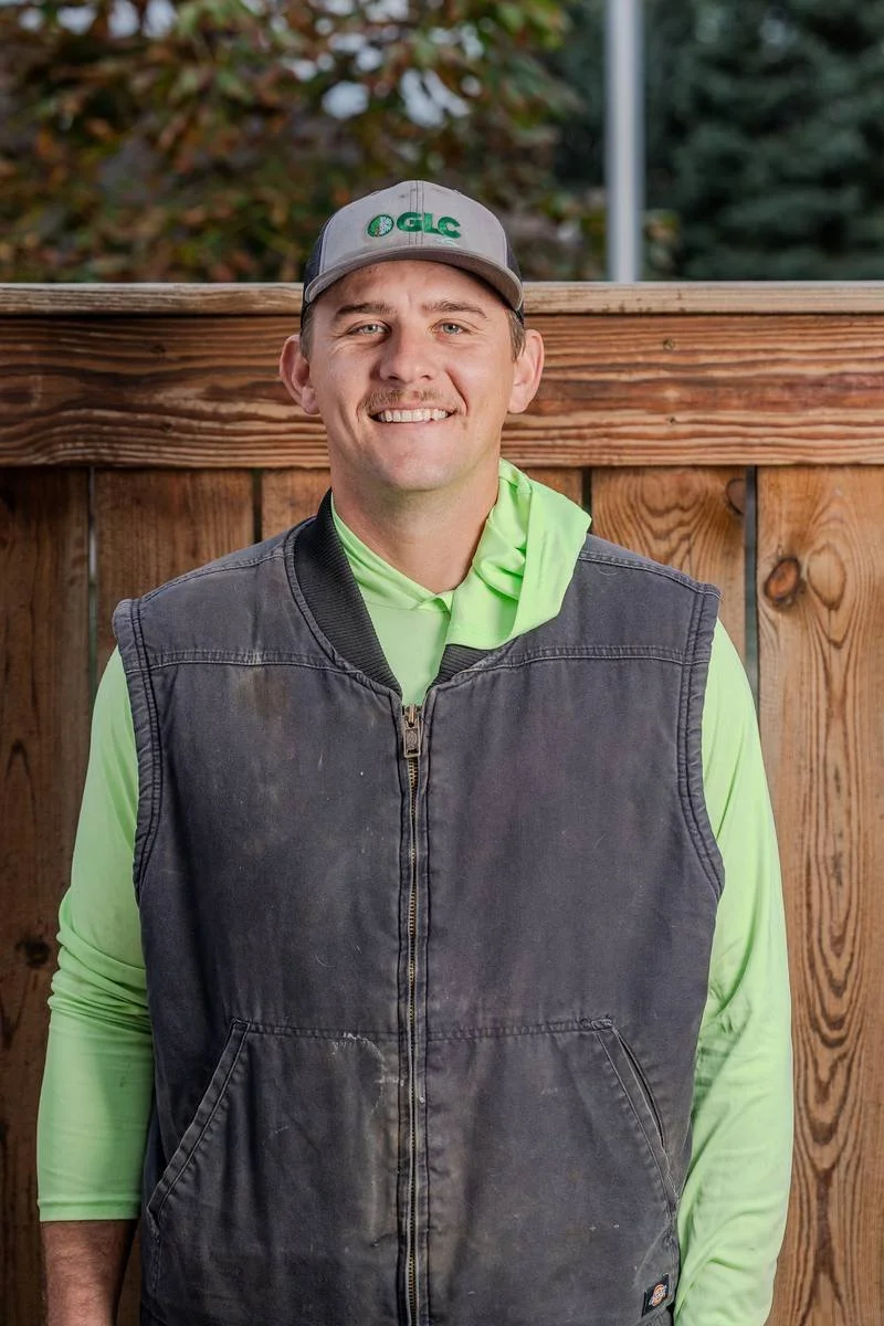 Justin K., Landscape Team Lead, in a work vest over a green GLC shirt — GLC Landscaping & Pools