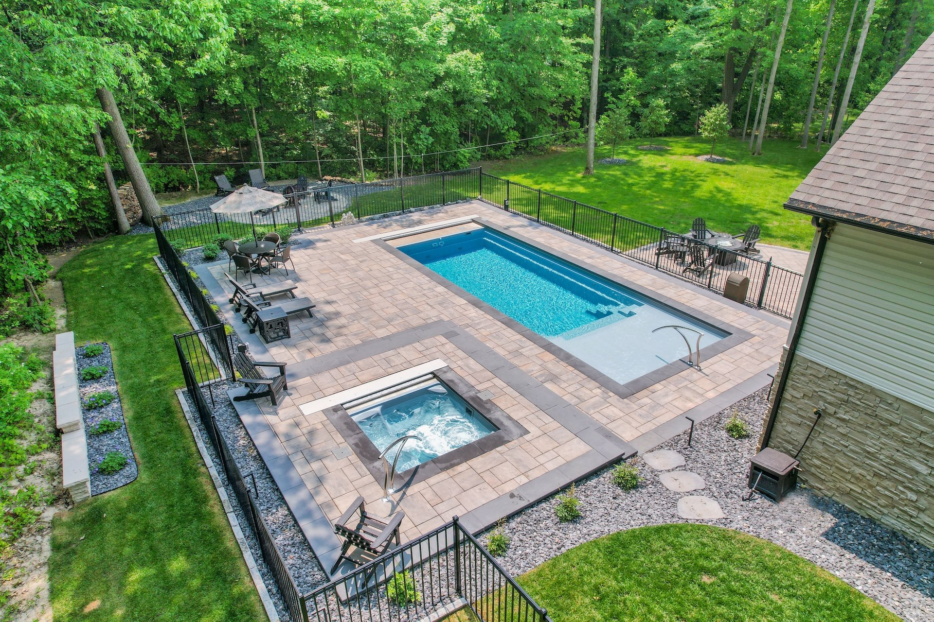 Fiberglass pool with integrated spa in Huron Township MI backyard