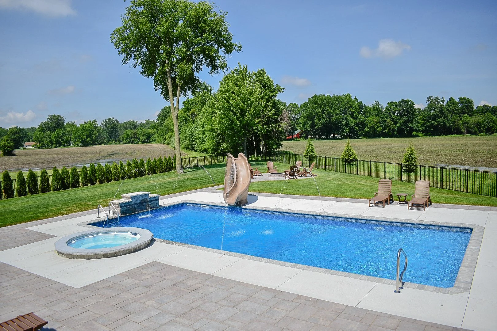 Curved hardscape detailing connecting poolside lounging areas, landscape beds, and entertainment spaces — GLC Lawn & Landscape