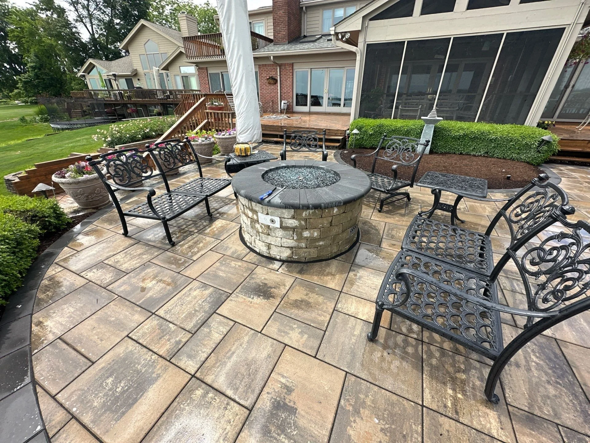 Built-in circular fire pit on paver patio near waterfront property