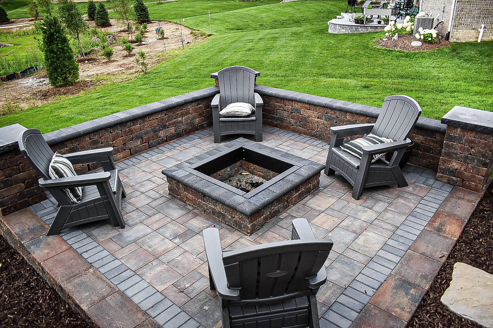 Decorative retaining wall features providing structure, elevation changes, and visual appeal in a backyard landscape — GLC Lawn & Landscape