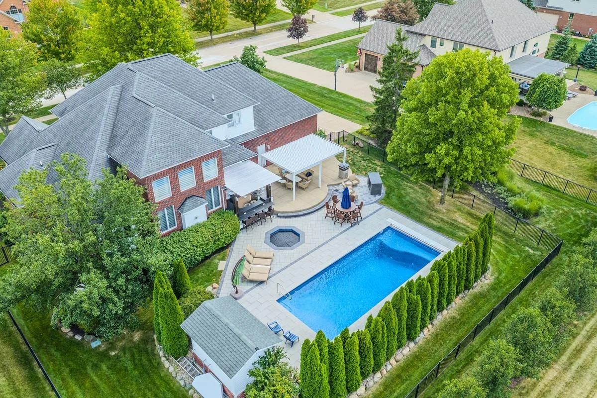 Aerial view of a rectangular pool with fire pit patio, pavilion and arborvitae privacy screen — GLC Landscaping & Pools