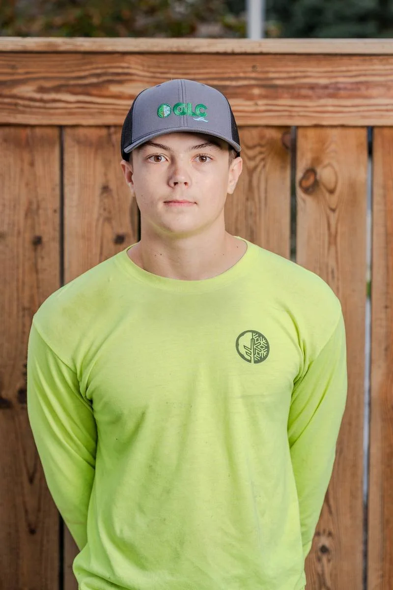 Caden, Landscape Specialist, in a bright yellow long-sleeve shirt and GLC cap — GLC Landscaping & Pools