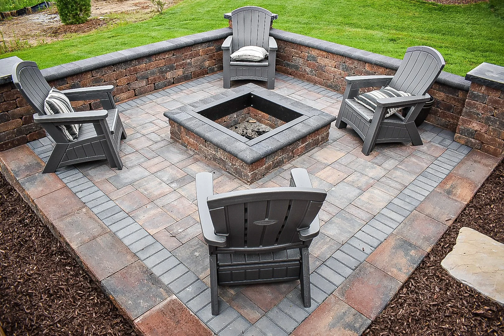 Backyard grading and hardscape transitions creating a smooth flow between patio spaces, planting beds, and lawn areas — GLC Lawn & Landscape