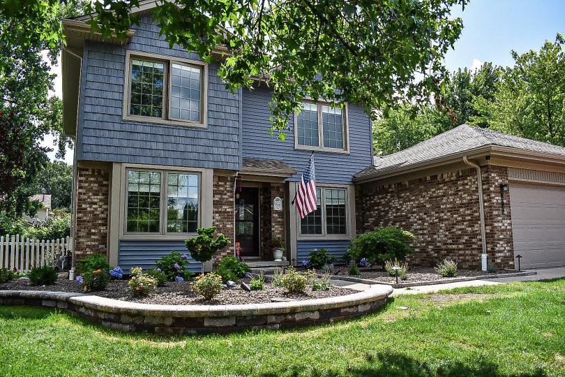 Front yard landscape redesign featuring curved planting beds, ornamental shrubs, and decorative stone accents — GLC Lawn & Landscape