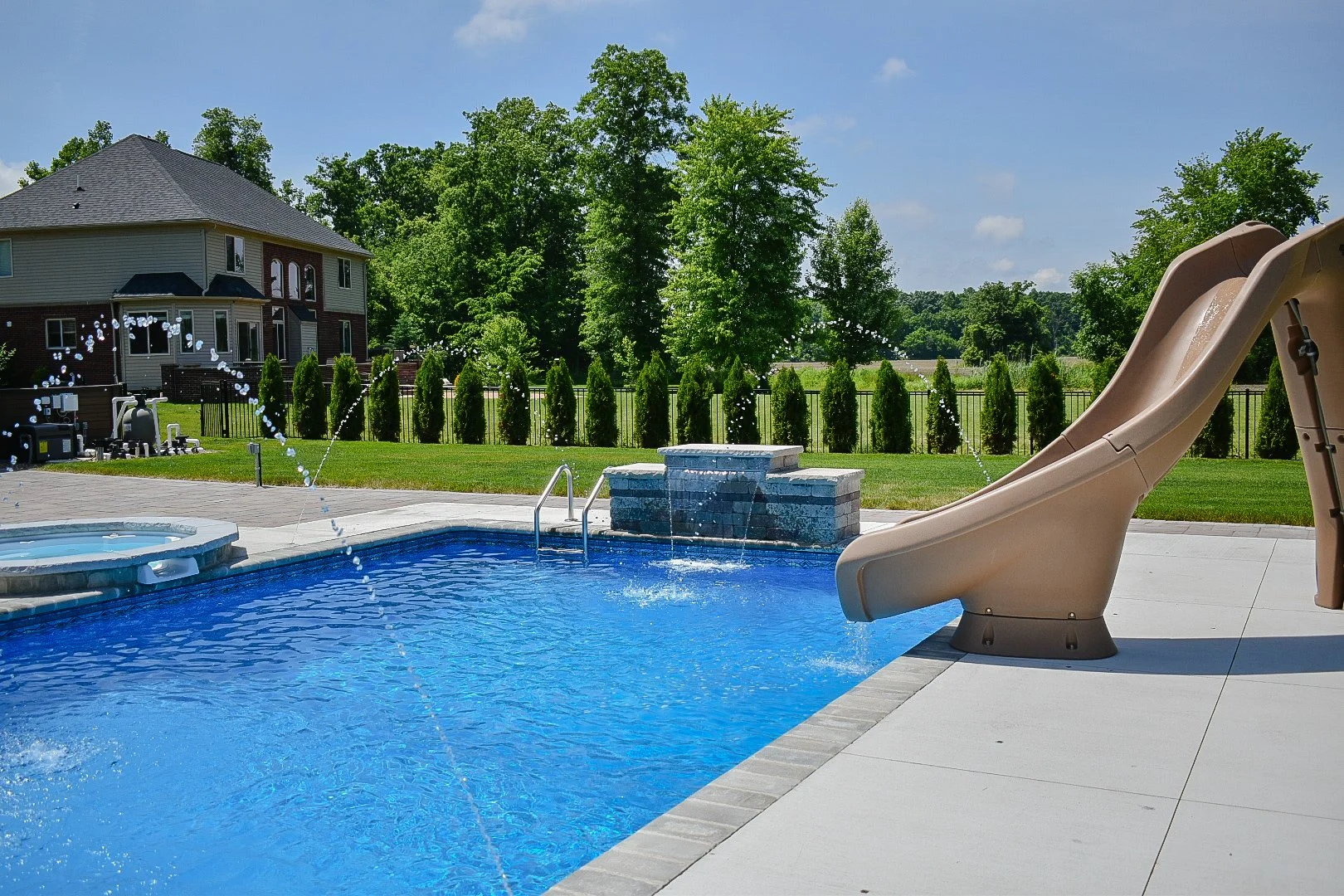 Large-format paver patio installation complementing a custom poolscape with spa and water feature elements — GLC Lawn & Landscape