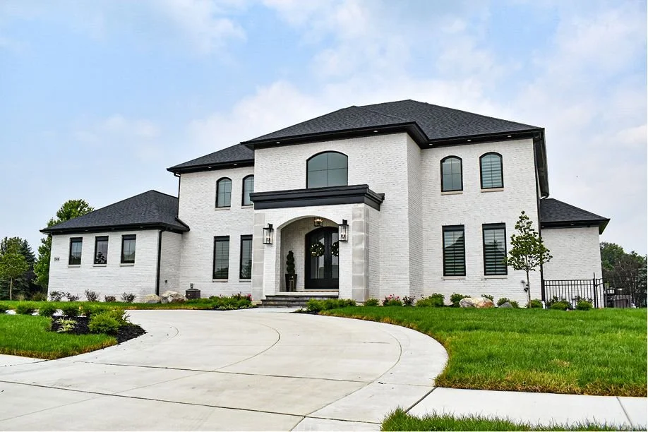 Modern home exterior with professional landscape design, new lawn installation, and clean front yard landscaping surrounding a curved driveway — GLC Lawn & Landscape