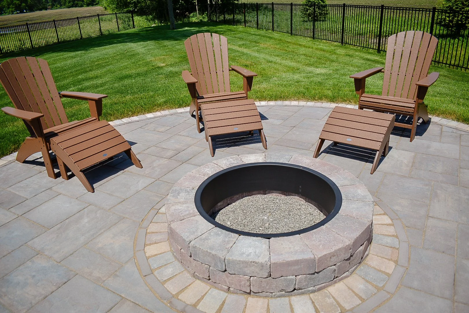 Luxury backyard entertainment space featuring an integrated spa, raised water feature wall, pool slide, and fire pit lounge area — GLC Lawn & Landscape