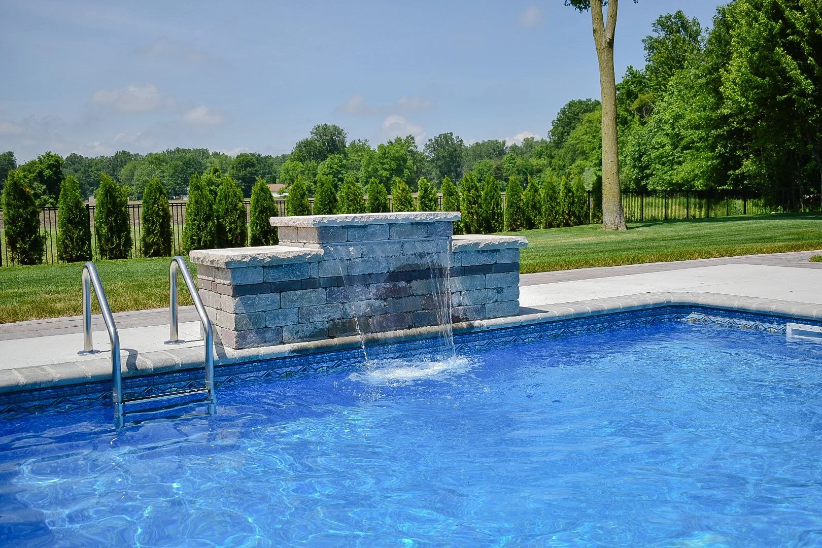 Curved hardscape detailing enhancing the flow and visual appeal of a custom poolscape and outdoor living area — GLC Lawn & Landscape