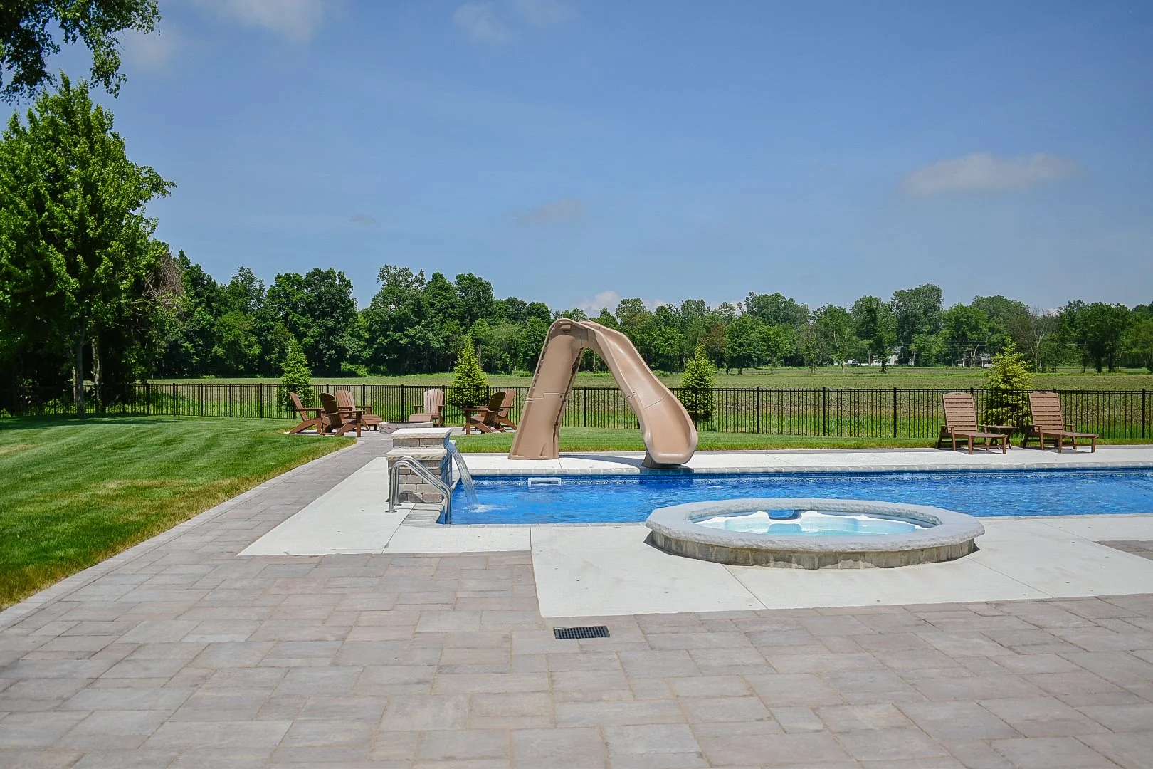 Landscape bed installation with colorful plantings surrounding a pool, spa, and outdoor entertainment space — GLC Lawn & Landscape