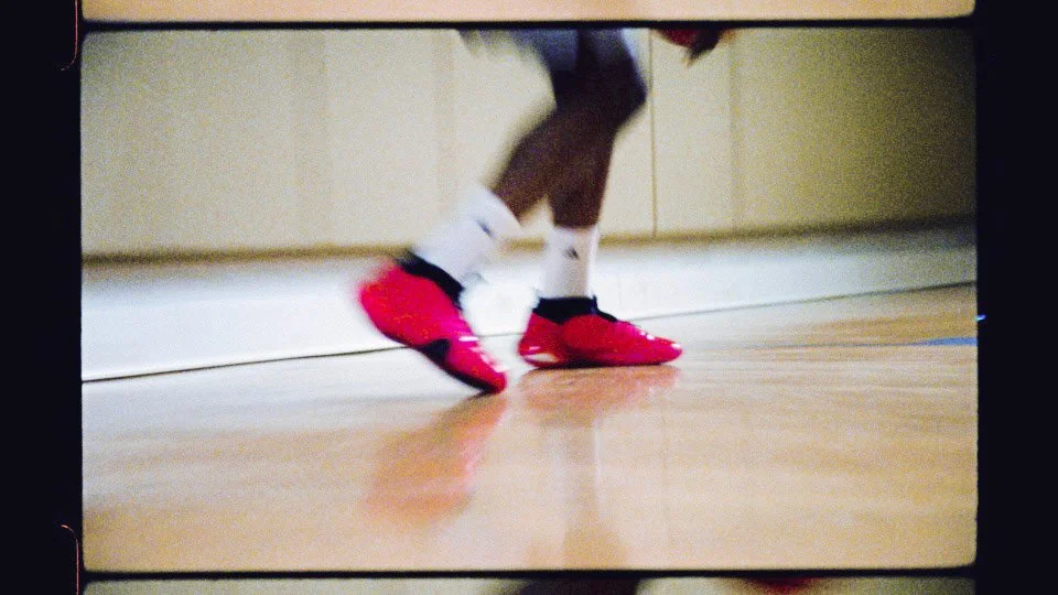Close-up of a person's legs wearing white socks and bright red athletic shoes, in position for sports or exercise.