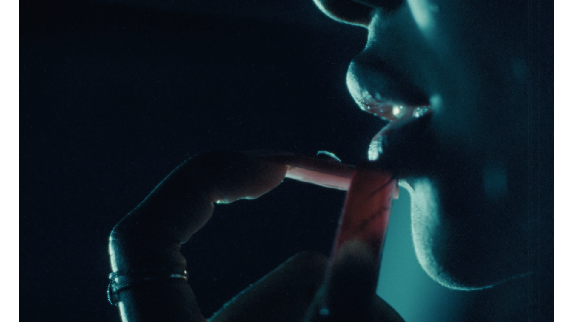 Close-up of a person smoking a cigarette in a dark setting with blue lighting.
