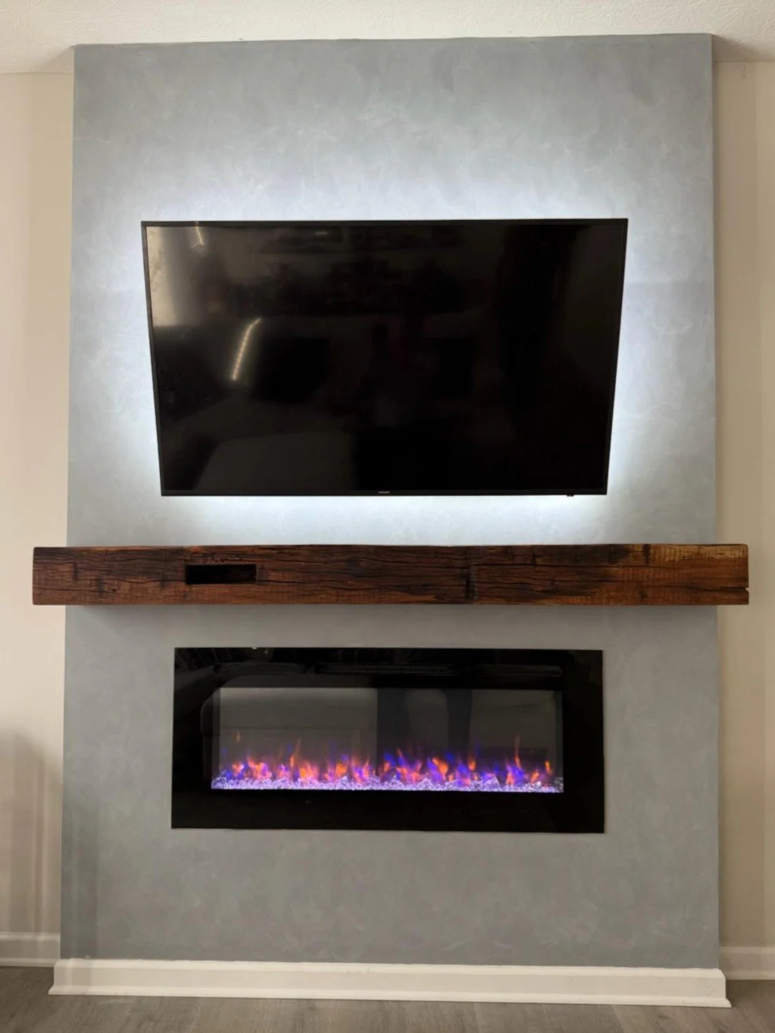 Living room fireplace with a mounted flat-screen TV above a wooden mantel and an electric fire insert below.