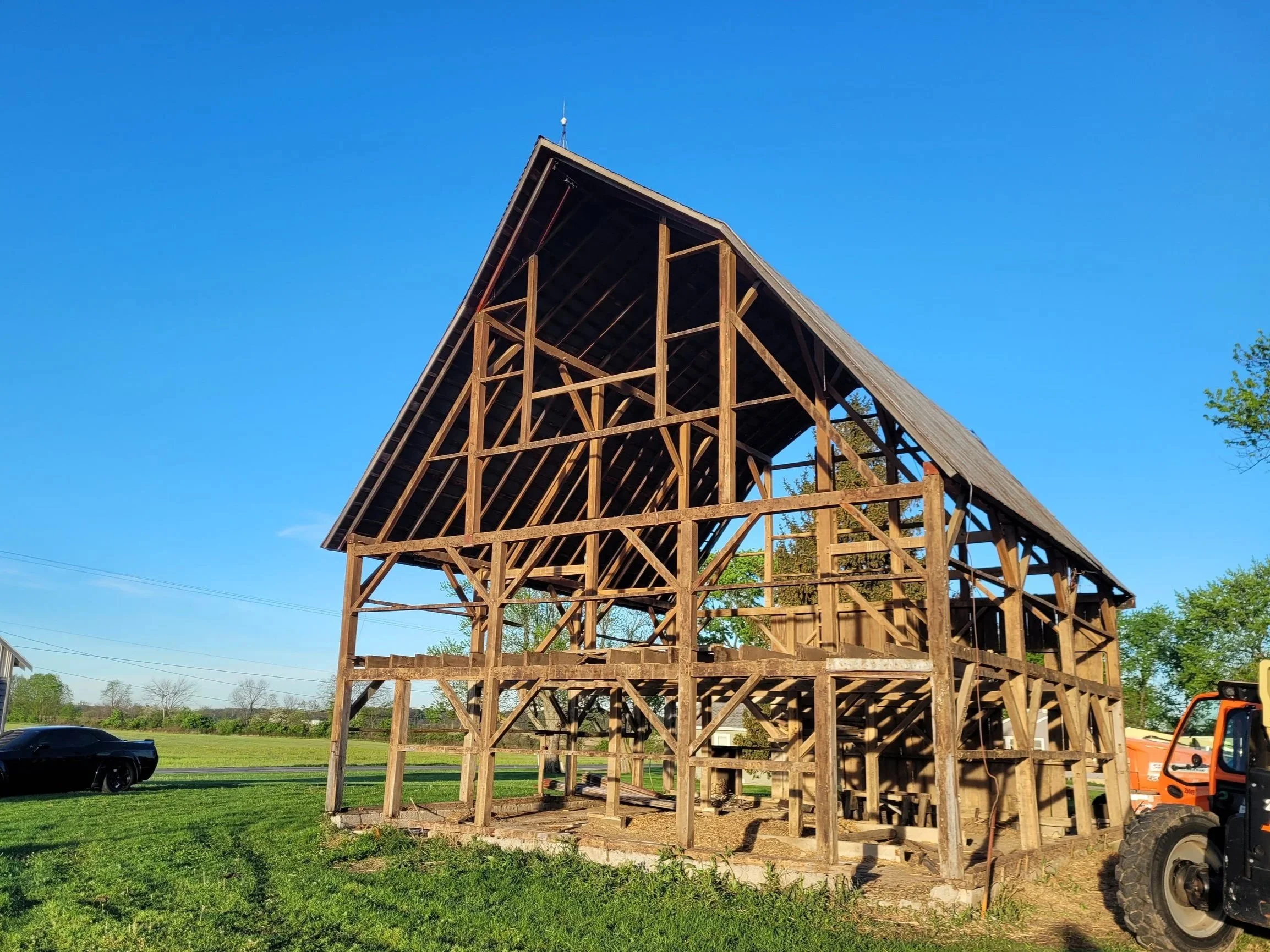 Under construction wooden house frame with clear blue sky and green grass.