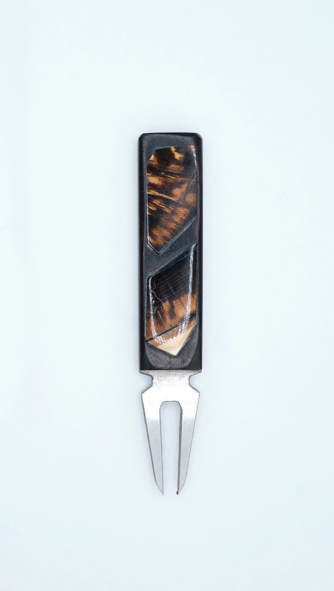 A cheese knife with a handle made of tortoiseshell patterned plastic and a stainless steel prong, placed on a white background.