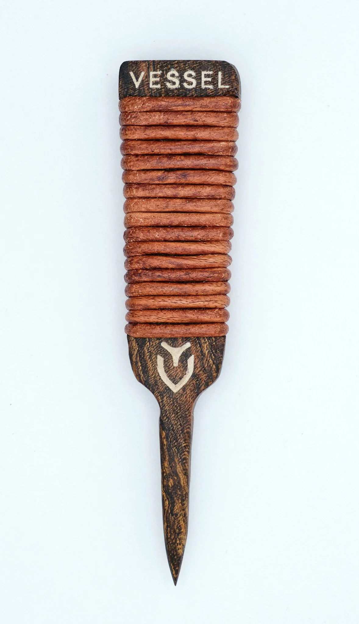 A hair pick with a wooden handle carved with the word 'VESSEL' on top, a logo on the handle, and a row of brown hair clips stacked on the handle.