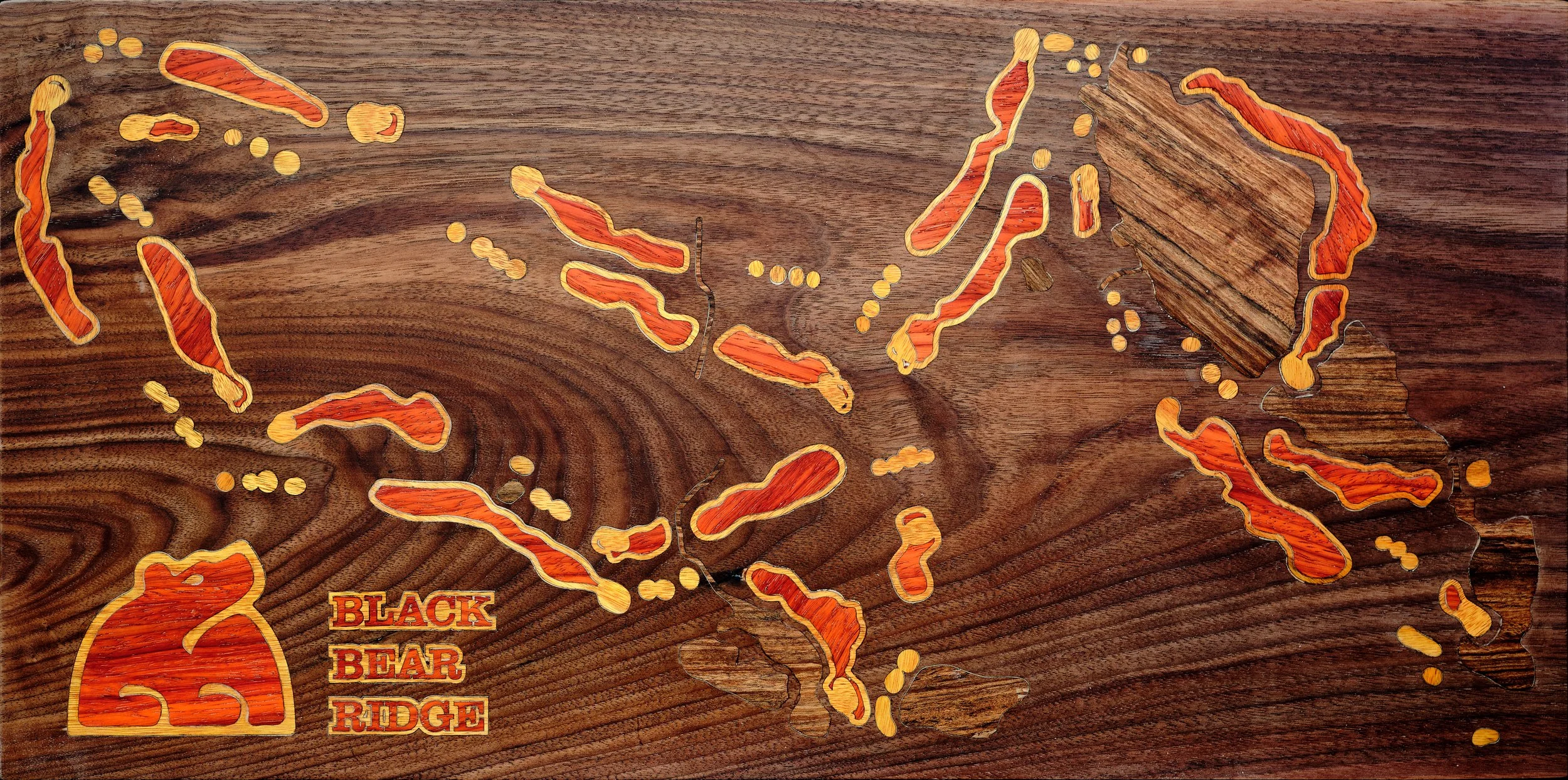 Wooden map of the Black Bear Ridge area showing highlighted trails and natural features with a brown background and a red bear logo in the bottom left corner reading "Black Bear Ridge."