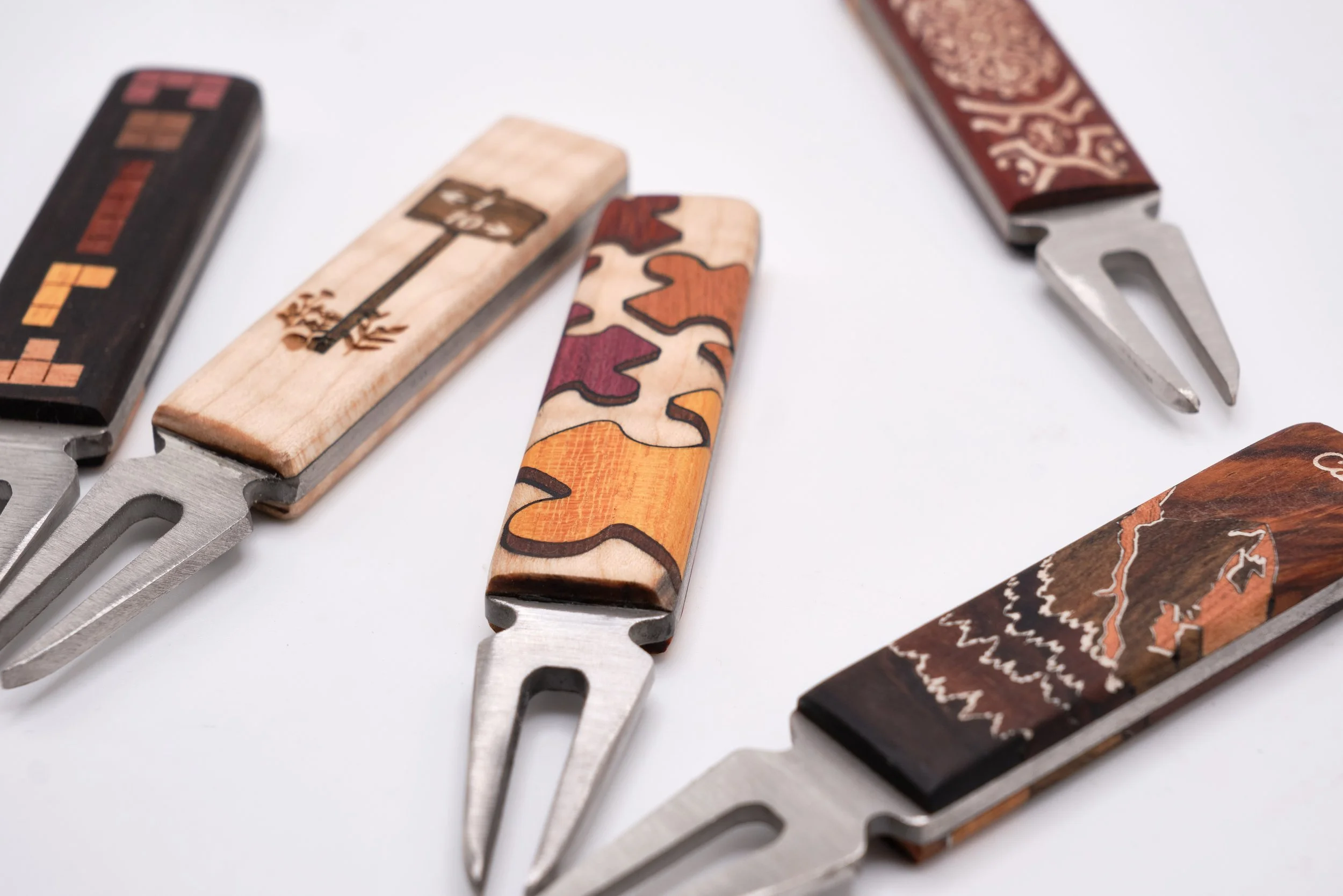 Five corkscrew bottle openers with decorative handles laid out on a white surface.