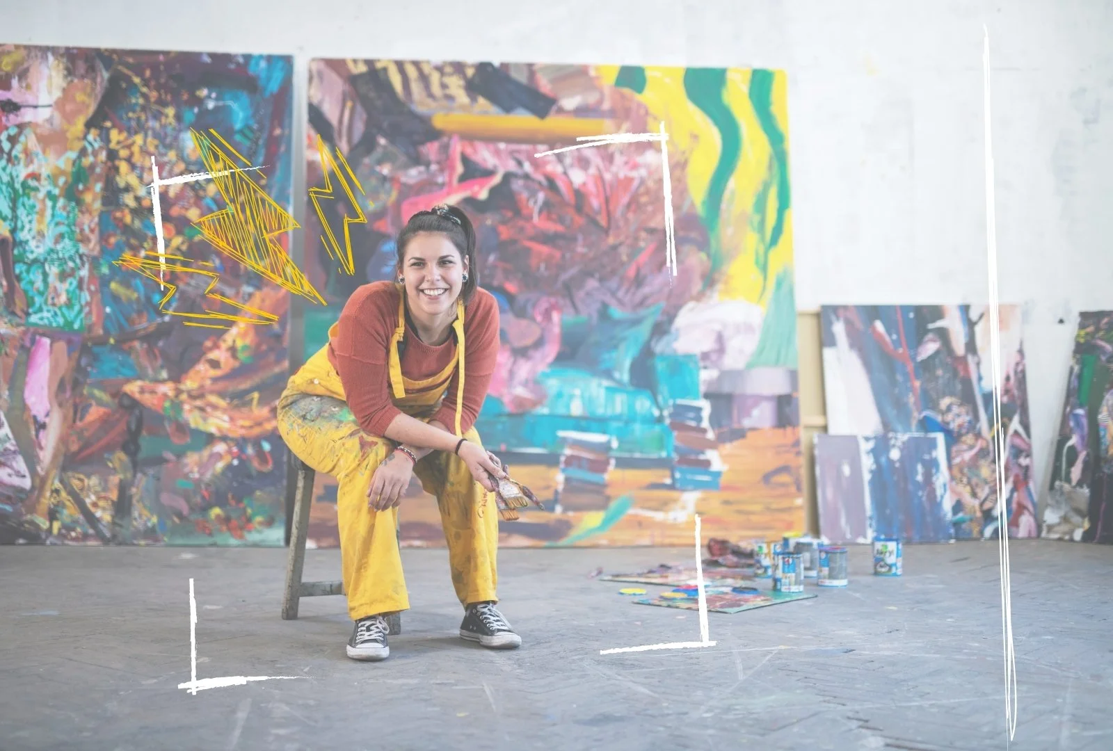 Artist sitting amongst paintings