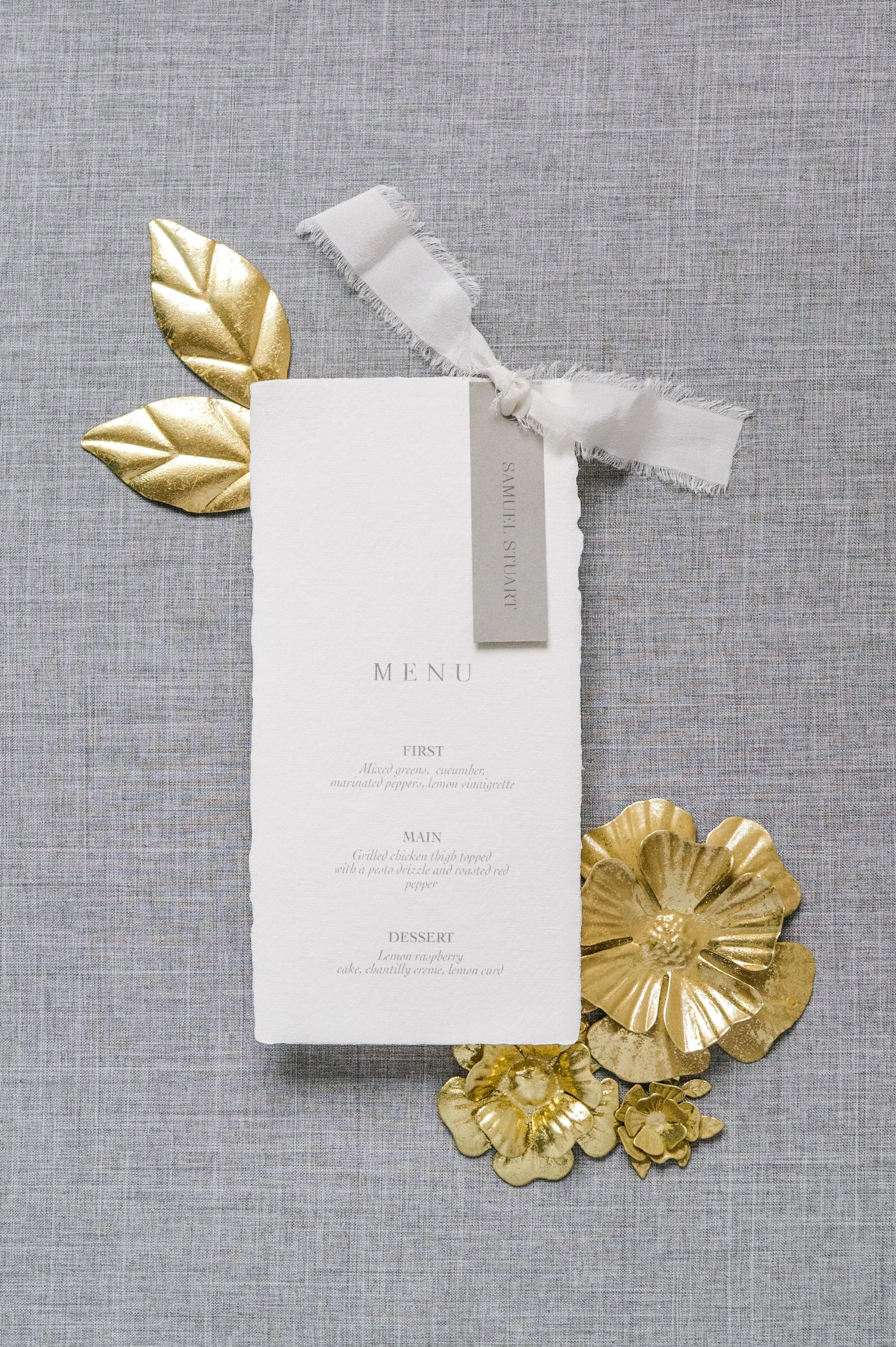 Elegant menu card decorated with gold metallic flowers and leaves on a gray textured background.