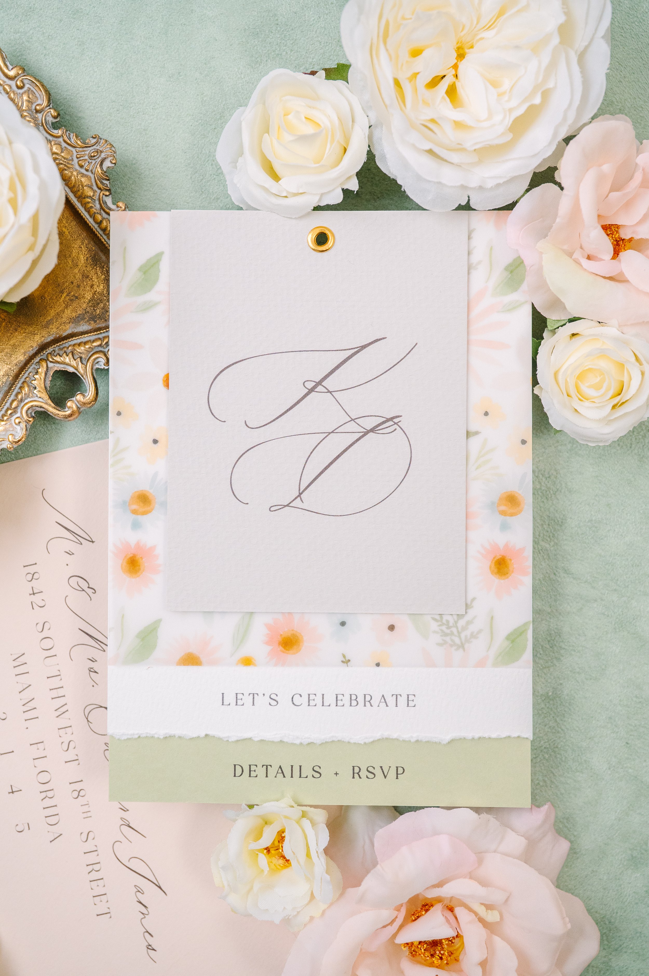 Wedding invitation with floral border, surrounded by white and pale pink roses, on a green background.