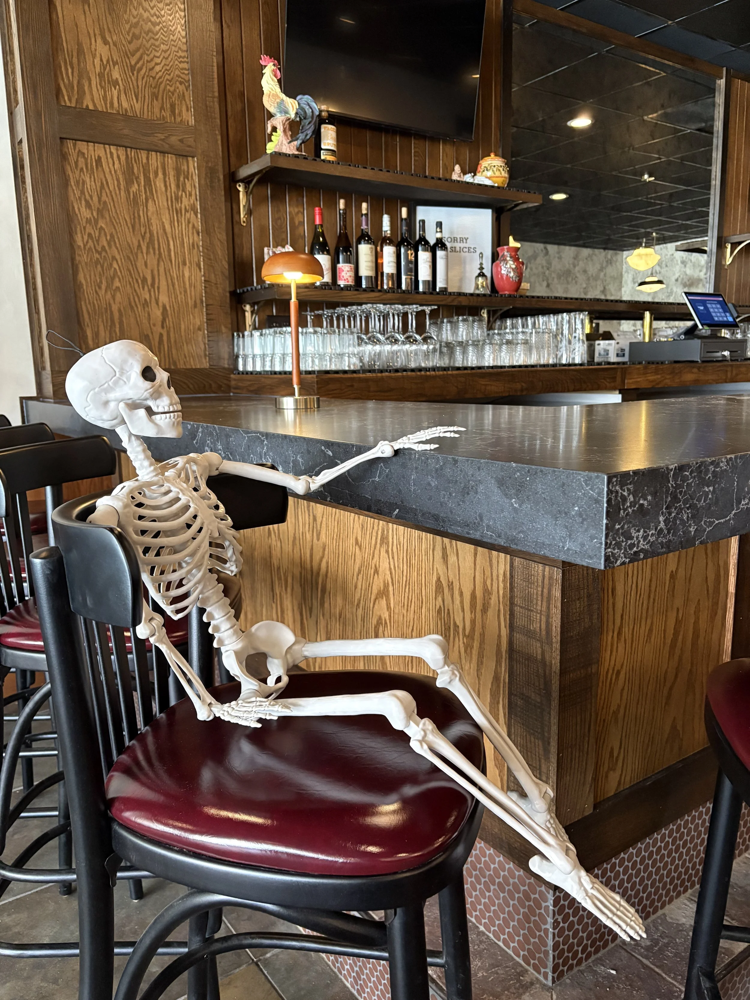 Interior of Pizzeria Di Lusso's bar in Shorewood, Wisconsin, featuring warm lighting, wood finishes, and a neighborhood pizzeria atmosphere.