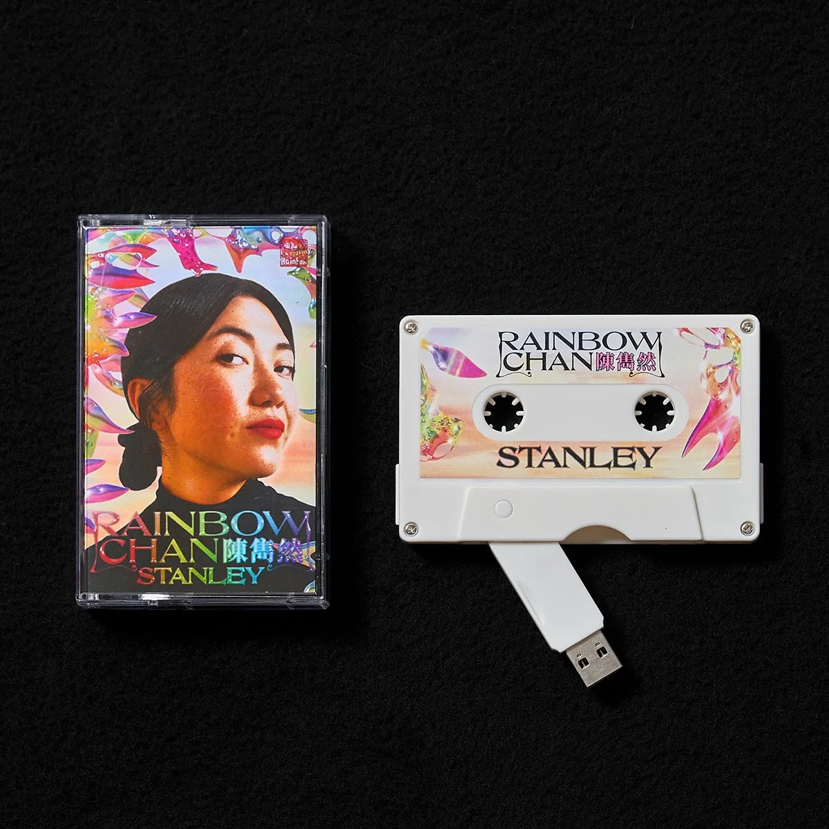 A cassette tape and its case, titled "Rainbow Chan" by Stanley, with colorful artwork and a woman's portrait on the cover.