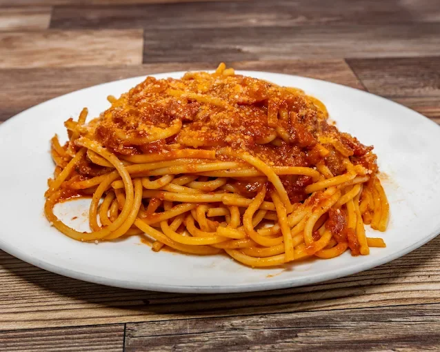Plate of spaghetti with meat sauce and grated cheese on top.