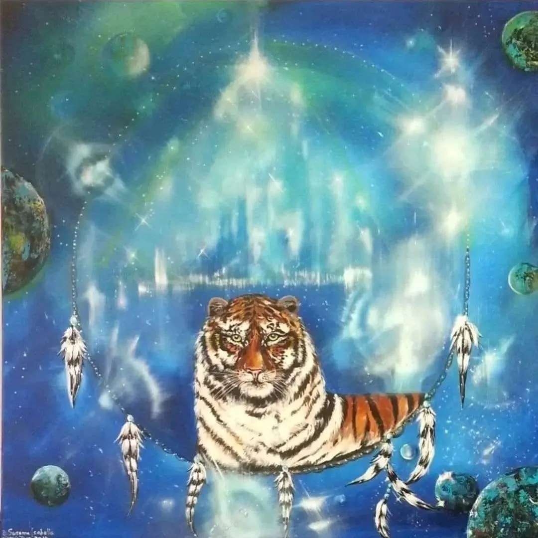Artwork featuring a realistic tiger resting on a dreamcatcher, set against a cosmic background with planets and bright stars.